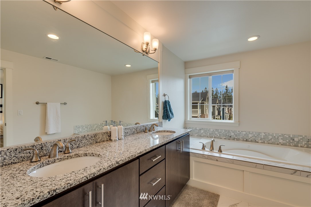 4408 186th Street Southeast Bothell, WA 98012 - Photo 17 of 23 a bathroom with a granite countertop sink a large mirror and a bathtub