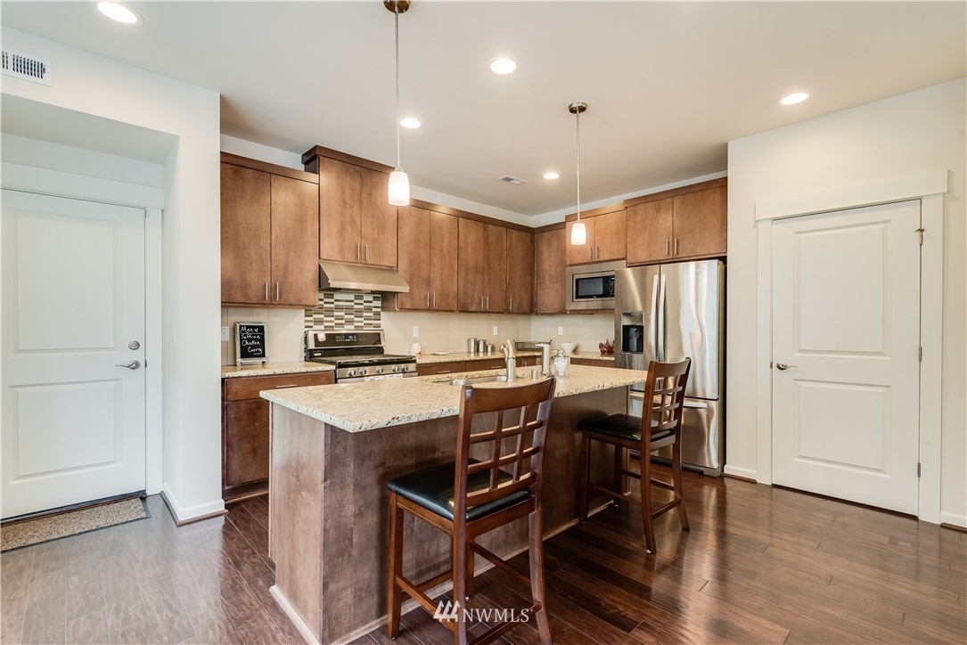 4408 186th Street Southeast Bothell, WA 98012 - Photo 9 of 23 a kitchen with a table a refrigerator a cabinets and stools