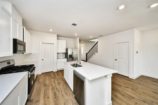 a kitchen with a sink a counter top space stainless steel appliances and cabinets