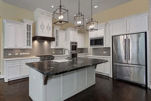 a kitchen with stainless steel appliances granite countertop a sink a center island a refrigerator and a stove