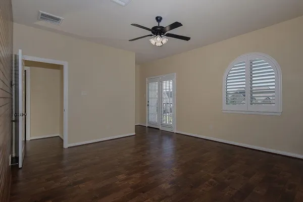 a view of an empty room with a window and wooden floor