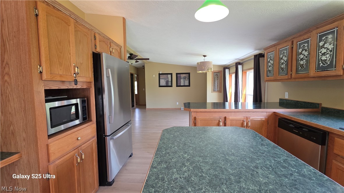 294 Twp 150 Road Sullivan, OH 44880 - Photo 14 of 39 Open-concept kitchen featuring extensive wood cabinetry, mottled green countertops, stainless steel appliances, and a central island