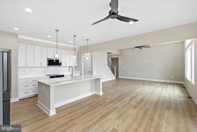 a view of an empty room with window and hardwood floor