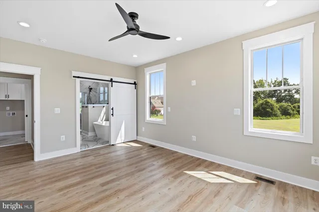 an empty room with wooden floor and windows