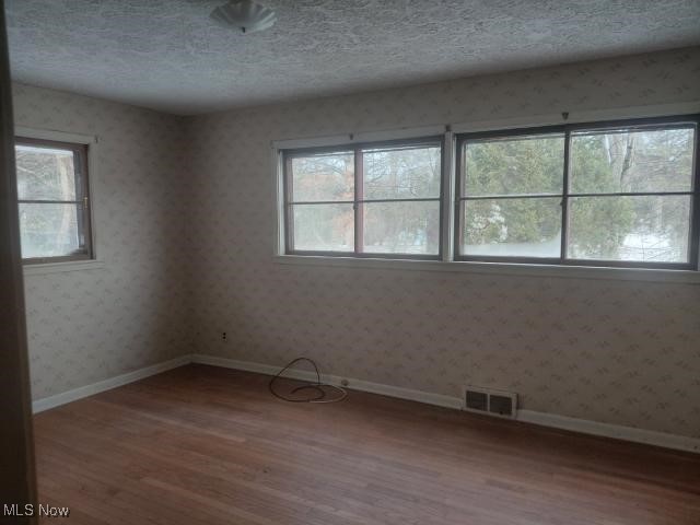 14849 Whitney Road Strongsville, OH 44136 - Photo 10 of 16 Spare room featuring wallpapered walls, light wood-style flooring, a textured ceiling, and plenty of natural light