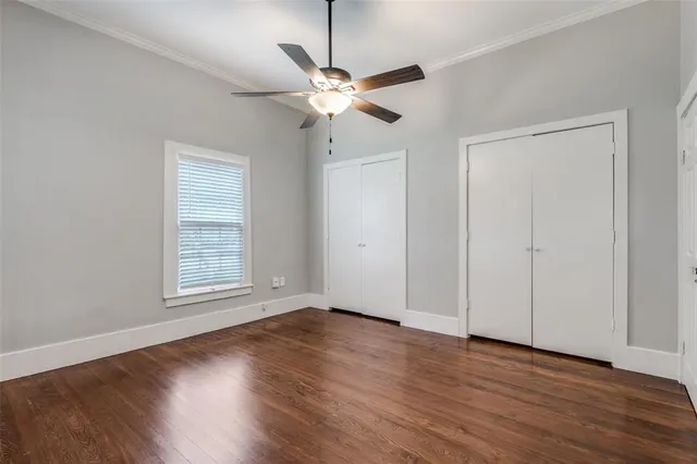 an empty room with wooden floor fan and windows