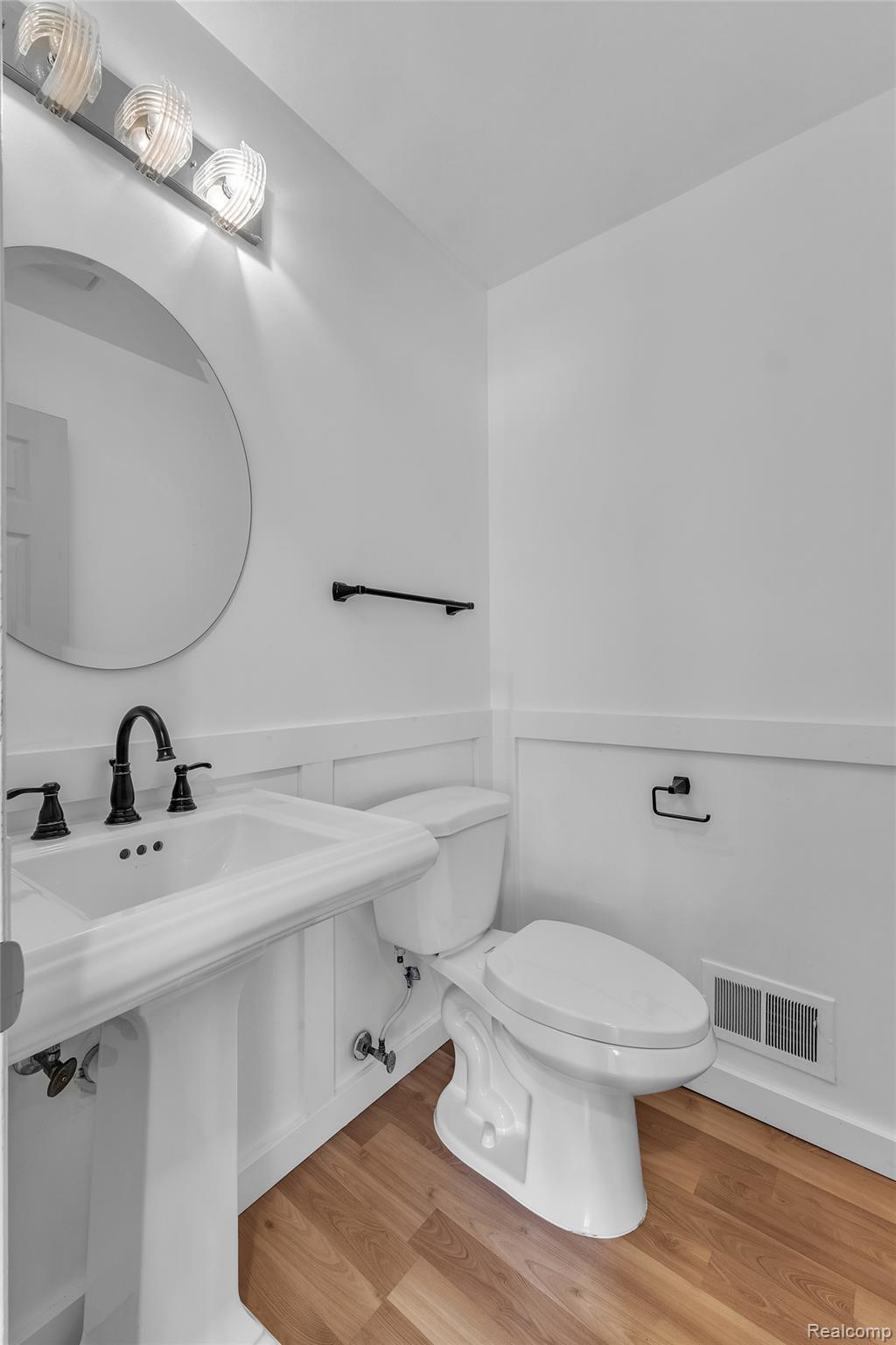 7000 Woonsocket Street Canton, MI 48187 - Photo 35 of 65 Pedestal sink with black-finish faucet, circular mirror, and modern vanity lighting
