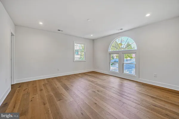 a view of an empty room with a window and wooden floor