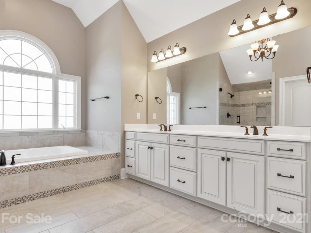 225 Cattle Ridge Road Marvin, NC 28173 - Photo 27 of 42 a spacious en suite bathroom with a granite countertop double vanity sink a large mirror a bathtub and next to a window