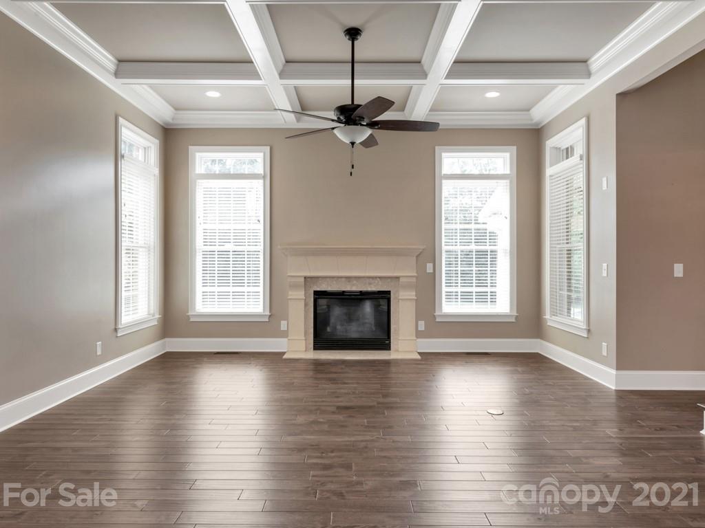 225 Cattle Ridge Road Marvin, NC 28173 - Photo 8 of 42 an empty room with wooden floor fireplace and windows