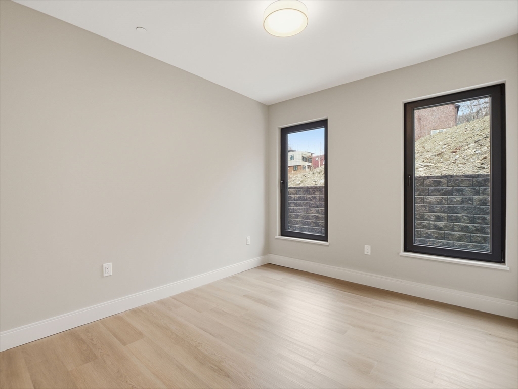 249 Corey Road, Unit 105 Boston, MA 02135 - Photo 14 of 41 an empty room with wooden floor and windows