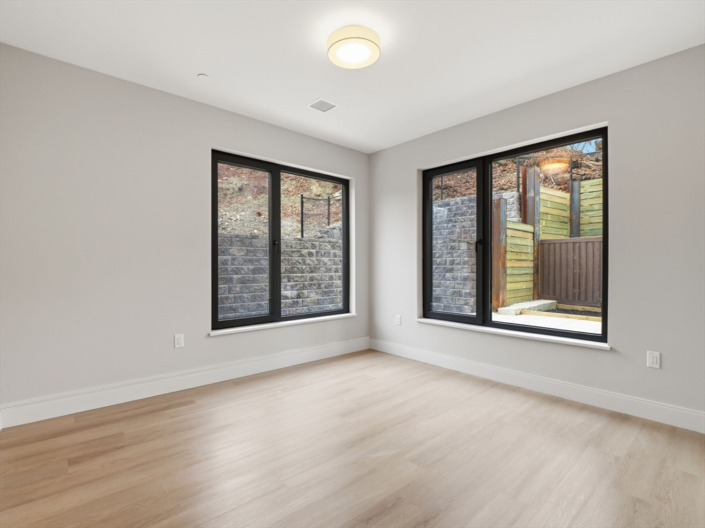 249 Corey Road, Unit 105 Boston, MA 02135 - Photo 18 of 41 an empty room with wooden floor and windows