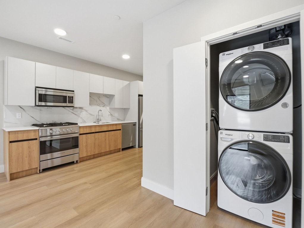 249 Corey Road, Unit 105 Boston, MA 02135 - Photo 2 of 41 a kitchen with stainless steel appliances granite countertop a stove a washer and dryer