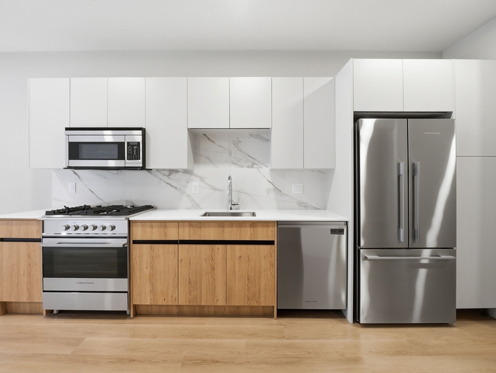249 Corey Road, Unit 105 Boston, MA 02135 - Photo 3 of 41 a kitchen with stainless steel appliances granite countertop a refrigerator stove and microwave