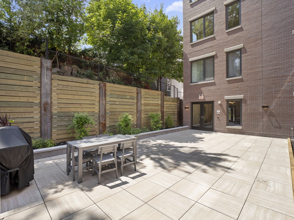 249 Corey Road, Unit 105 Boston, MA 02135 - Photo 36 of 41 a view of a patio with a table and chairs and wooden fence