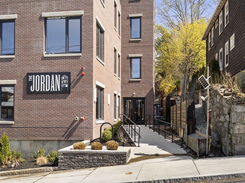 249 Corey Road, Unit 105 Boston, MA 02135 - Photo 39 of 41 a view of a brick house with plants and large tree