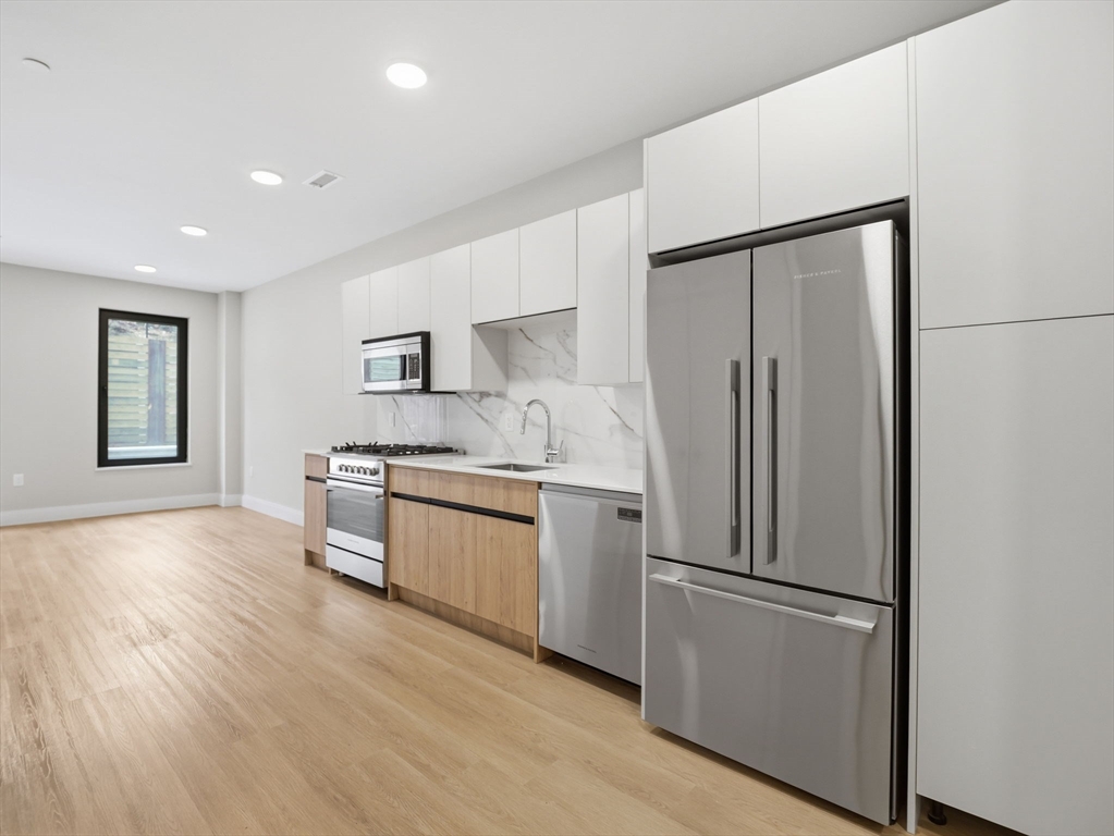 249 Corey Road, Unit 105 Boston, MA 02135 - Photo 4 of 41 a kitchen with stainless steel appliances a refrigerator and a stove top oven