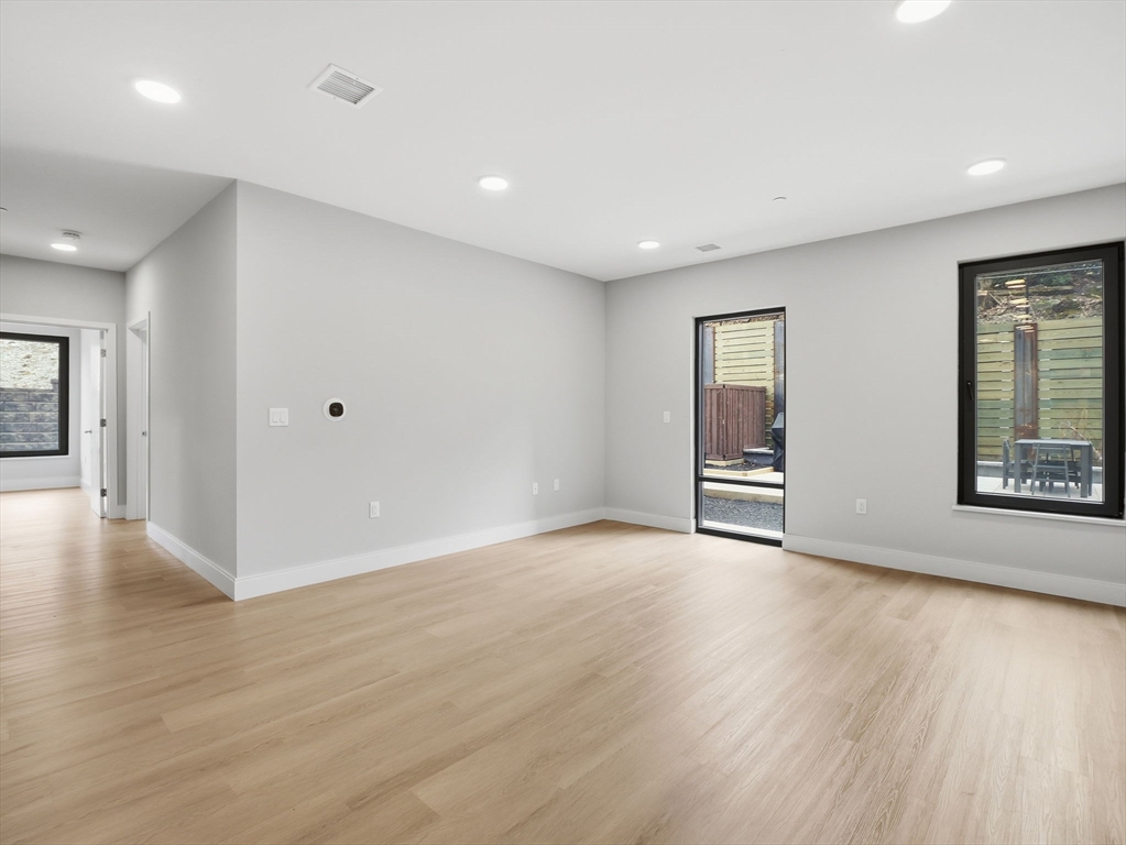 249 Corey Road, Unit 105 Boston, MA 02135 - Photo 10 of 41 a view of an empty room with wooden floor and a window