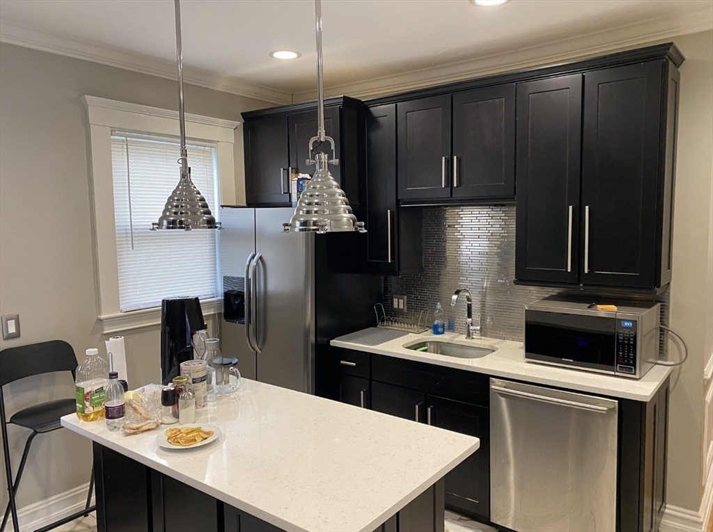 19 Pleasant Street, Unit 1 Boston, MA 02125 - Photo 2 of 10 a kitchen with a refrigerator a stove a sink a dining table and chairs