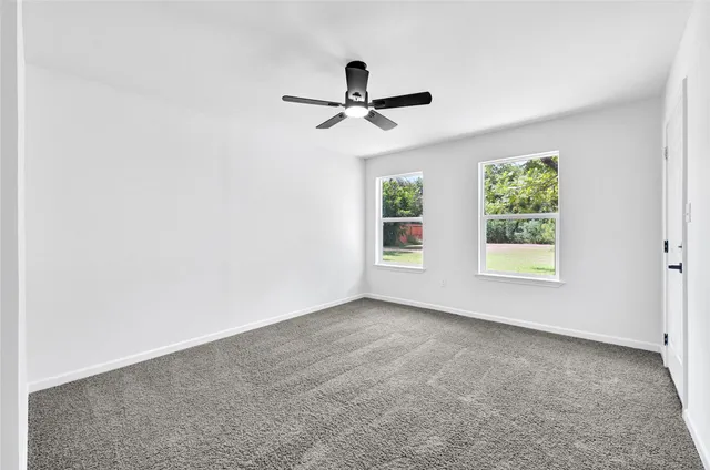an empty room with windows and ceiling fan