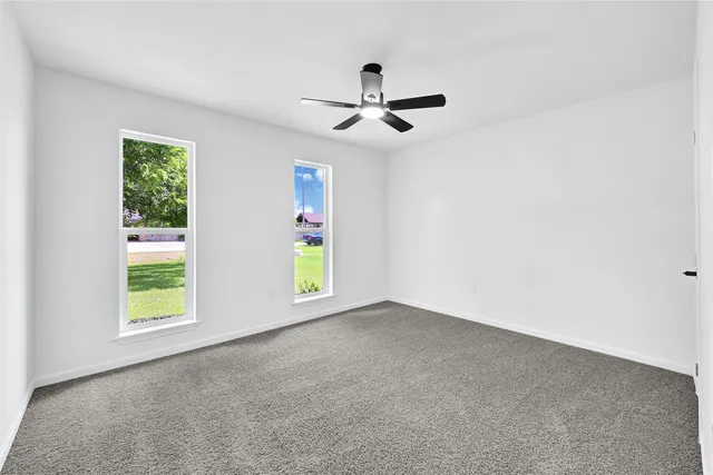 an empty room with windows and ceiling fan view
