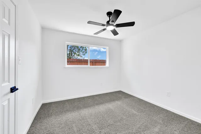an empty room with a window and a fan