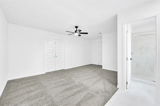an empty room with closet and a ceiling fan