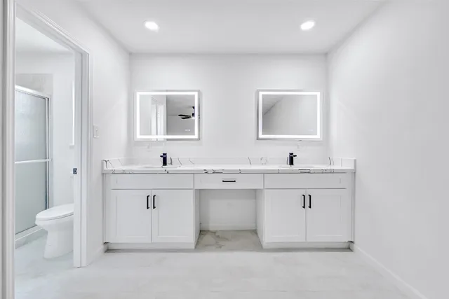 a spacious bathroom with a double vanity sink toilet and a mirror