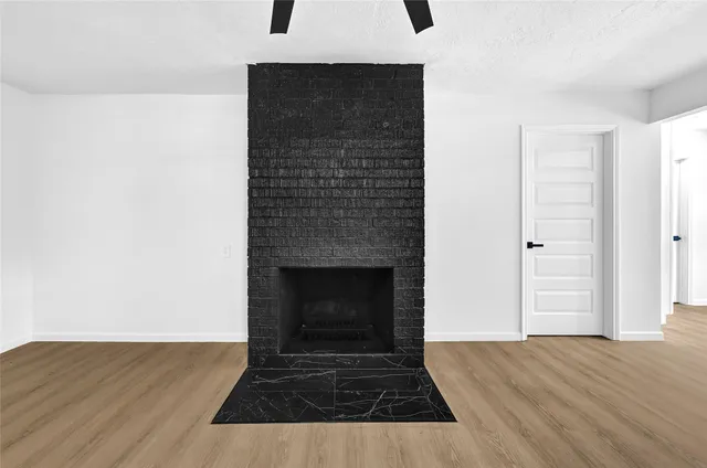 a view of empty room with wooden floor and fireplace