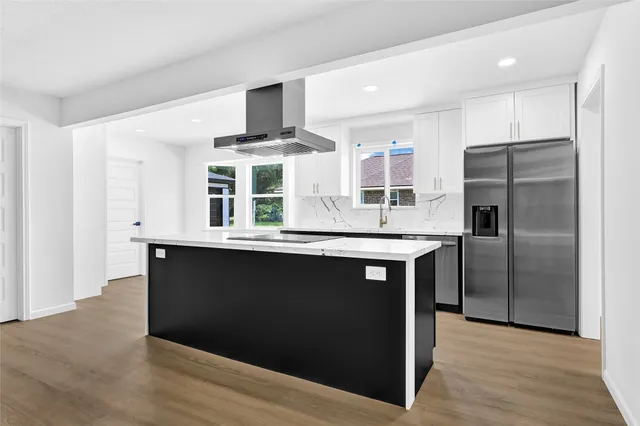 a kitchen with stainless steel appliances granite countertop a refrigerator and a stove top oven