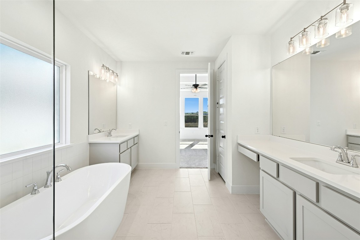 1533 Rodeo Ridge Drive Georgetown, TX 78628 - Photo 13 of 34 Bathroom featuring two vanities, a soaking tub, and ceiling fan