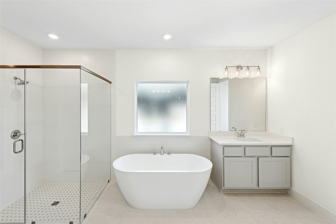 1533 Rodeo Ridge Drive Georgetown, TX 78628 - Photo 14 of 34 Bathroom with a freestanding tub, vanity, a stall shower, recessed lighting, and tile walls
