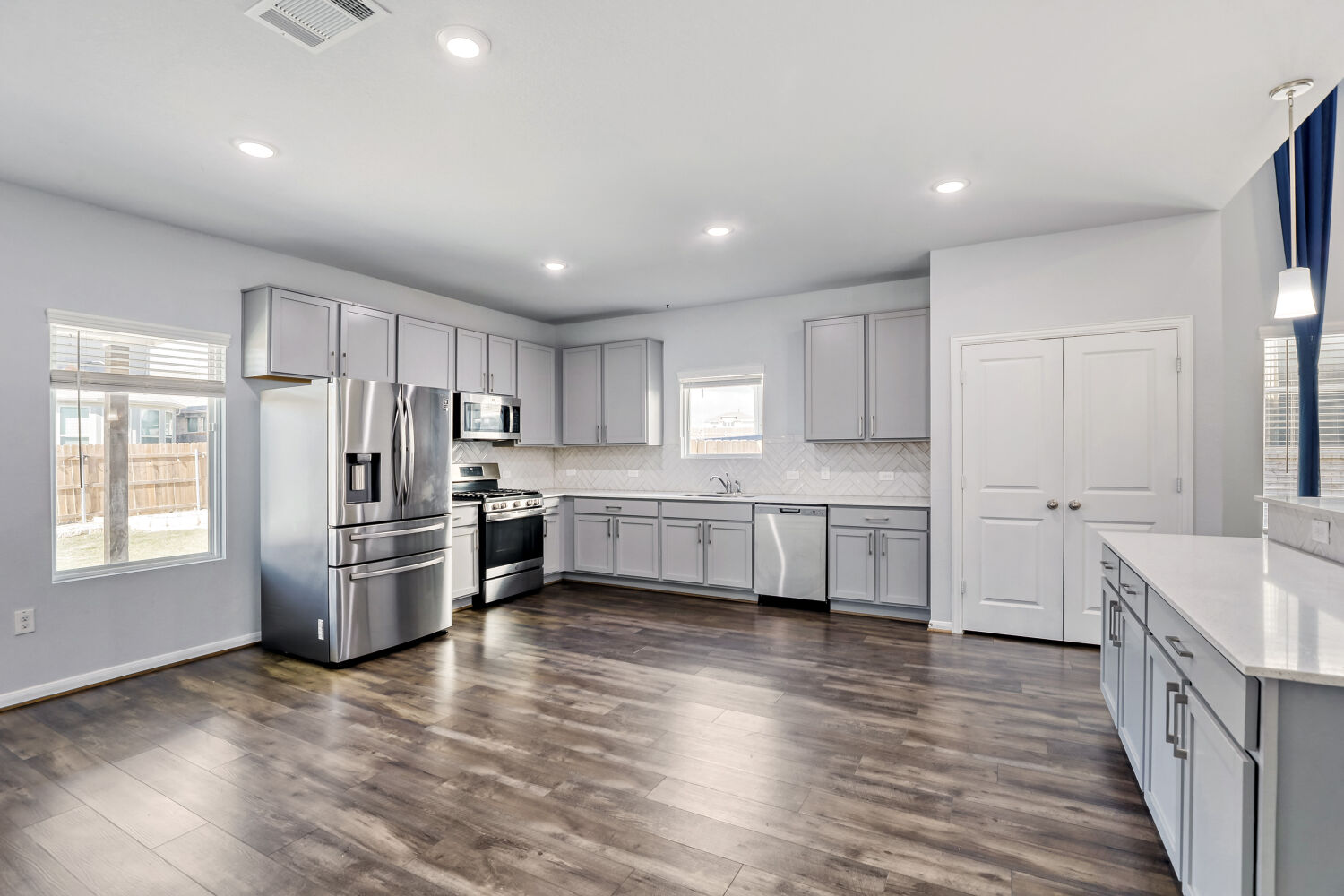 6601 Avila Way Pflugerville, TX 78660 - Photo 9 of 28 Kitchen featuring gray cabinetry, stainless steel appliances, pendant lighting, dark wood-style flooring, and tasteful backsplash