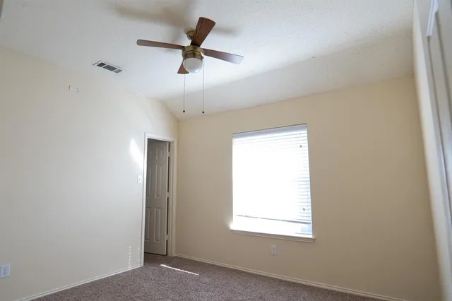 an empty room with a ceiling fan and a window