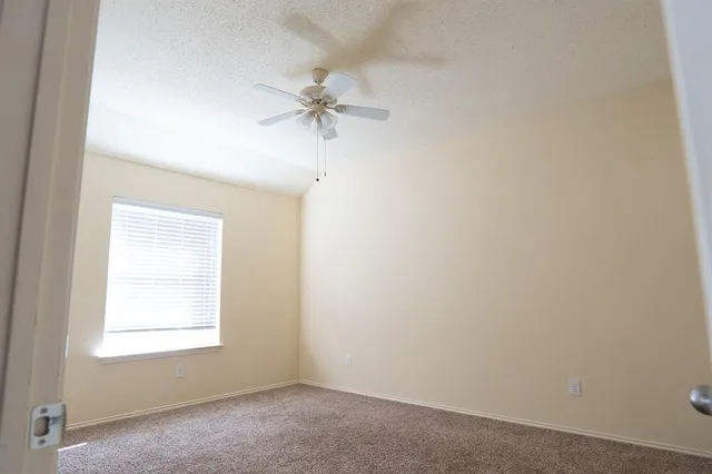 an empty room with a window and a fan