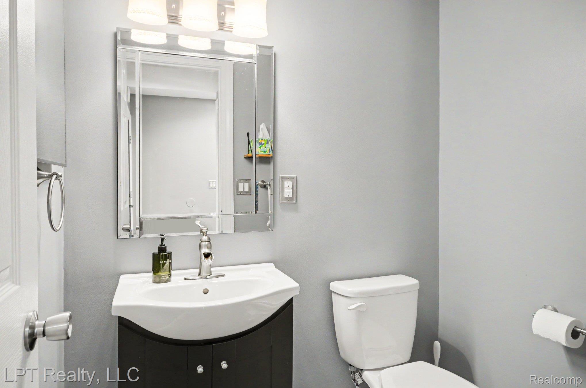 829 Langdon Court Rochester, MI 48307 - Photo 18 of 31 Bathroom featuring a vanity with an integrated sink, a contemporary mirror, and a three-light fixture
