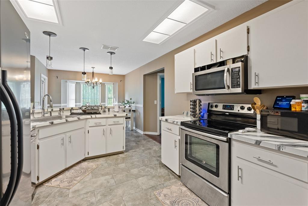 5065 Southwest 128th Street Ocala, FL 34473 - Photo 26 of 31 a kitchen with granite countertop white cabinets stainless steel appliances and a counter space