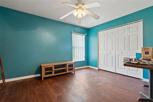 an empty room with windows and ceiling fan