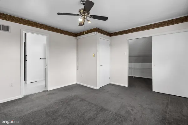 an empty room with windows and ceiling fan