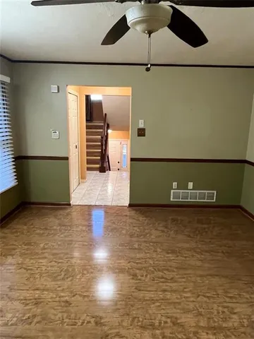 a view of an empty room with a chandelier fan and a kitchen