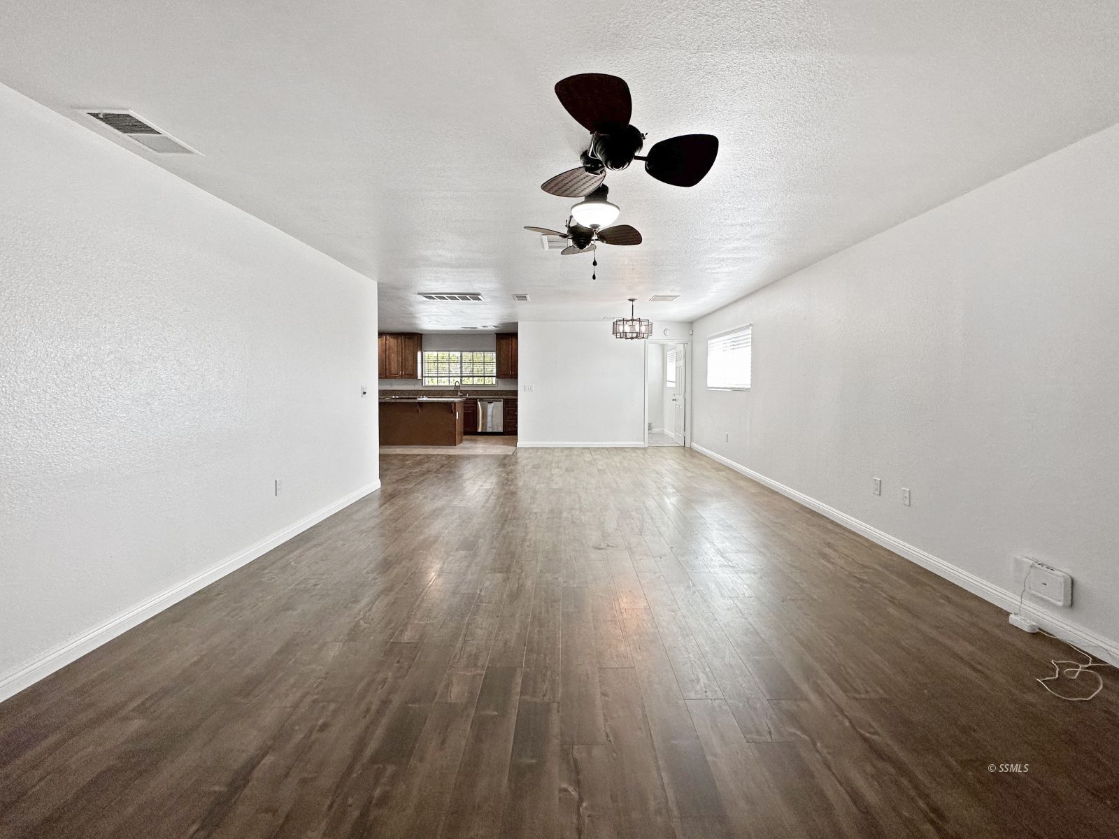 504 Randall Street Ridgecrest, CA 93555 - Photo 3 of 29 an empty room with wooden floor ceiling fan and window
