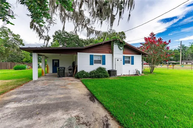 a view of a house with a yard and palm trees