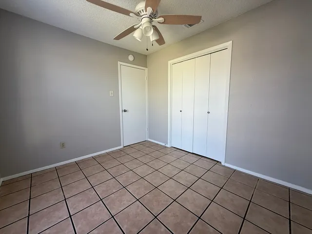 a view of an empty room and chandelier fan