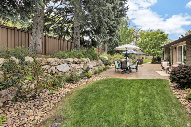 1350 Canyon Park Road Bountiful, UT 84010 - Photo 5 of 38 Expansive backyard featuring a manicured lawn, a large stamped concrete patio, and a stone retaining wall