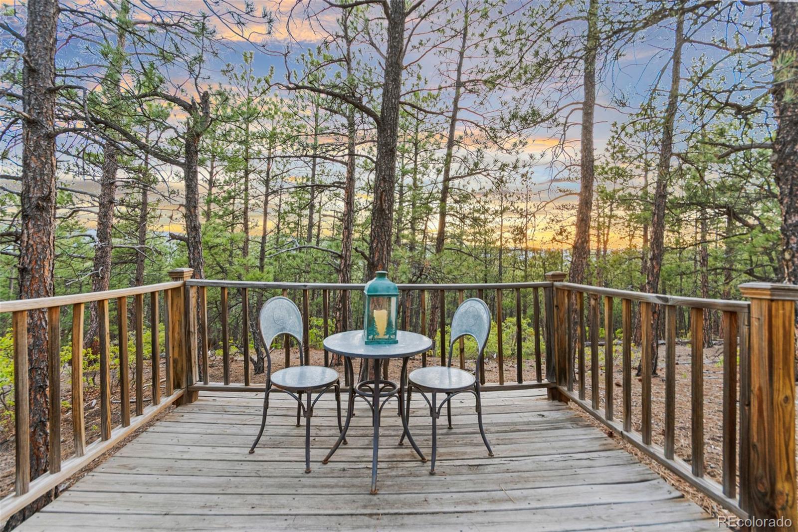 5090 South Perry Park Road Sedalia, CO 80135 - Photo 42 of 50 a set of chair on a deck with large trees