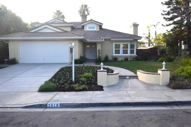 a front view of a house with a yard and potted plants