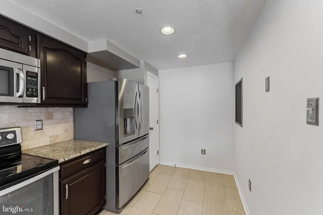 a kitchen with stainless steel appliances granite countertop a refrigerator and a stove top oven