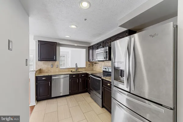 a large kitchen with stainless steel appliances granite countertop a refrigerator and a sink