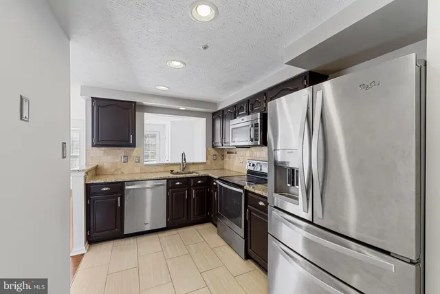 a large kitchen with stainless steel appliances granite countertop a refrigerator and a sink