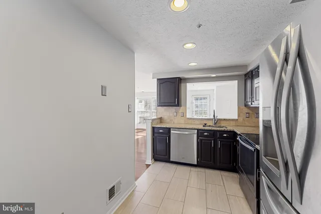 a large kitchen with stainless steel appliances granite countertop a refrigerator and a sink